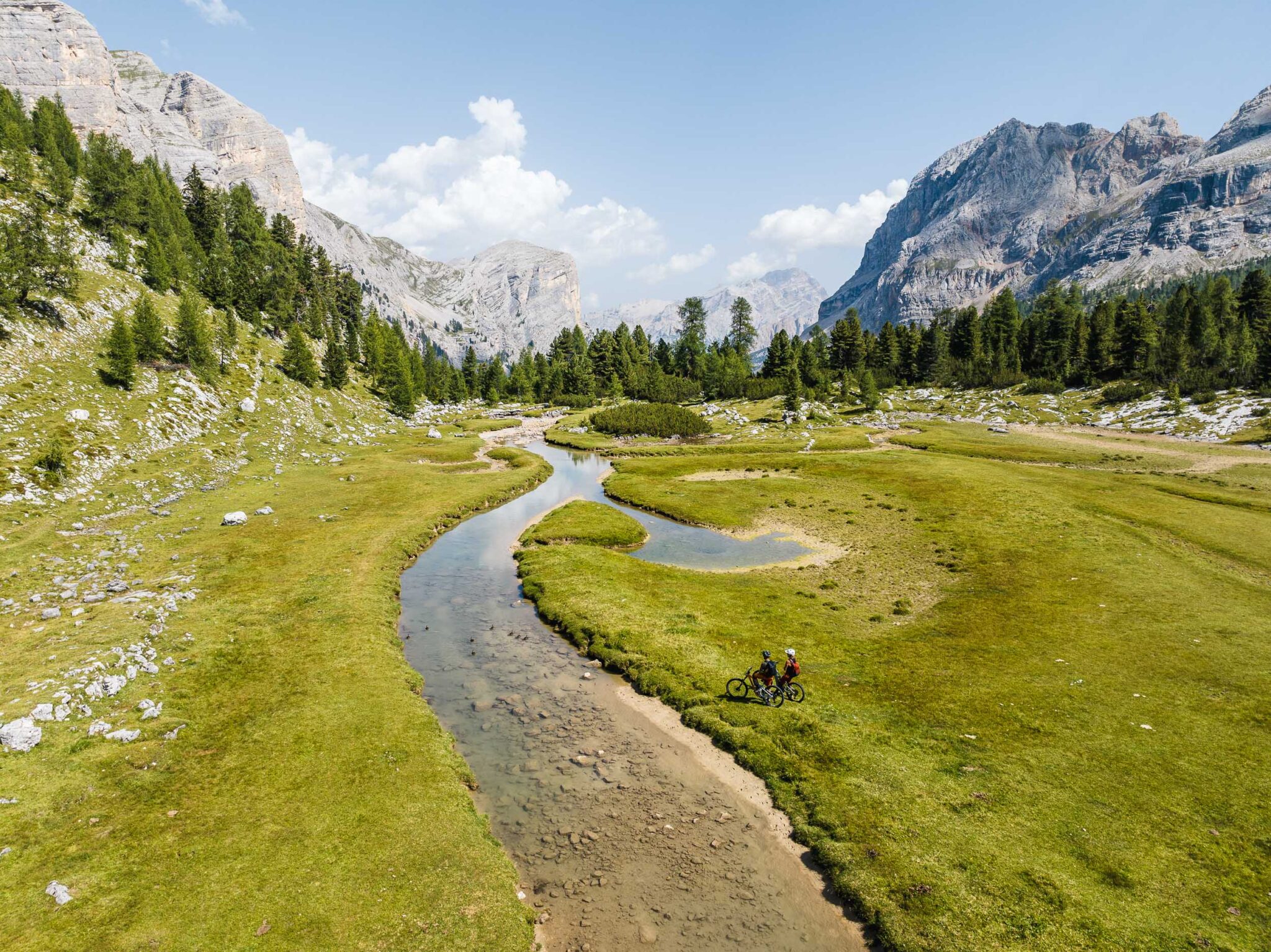 Zwei Mountainbiker machen Pause auf der Fanes Hochebene. Im Hintergrund die Dolomiten.