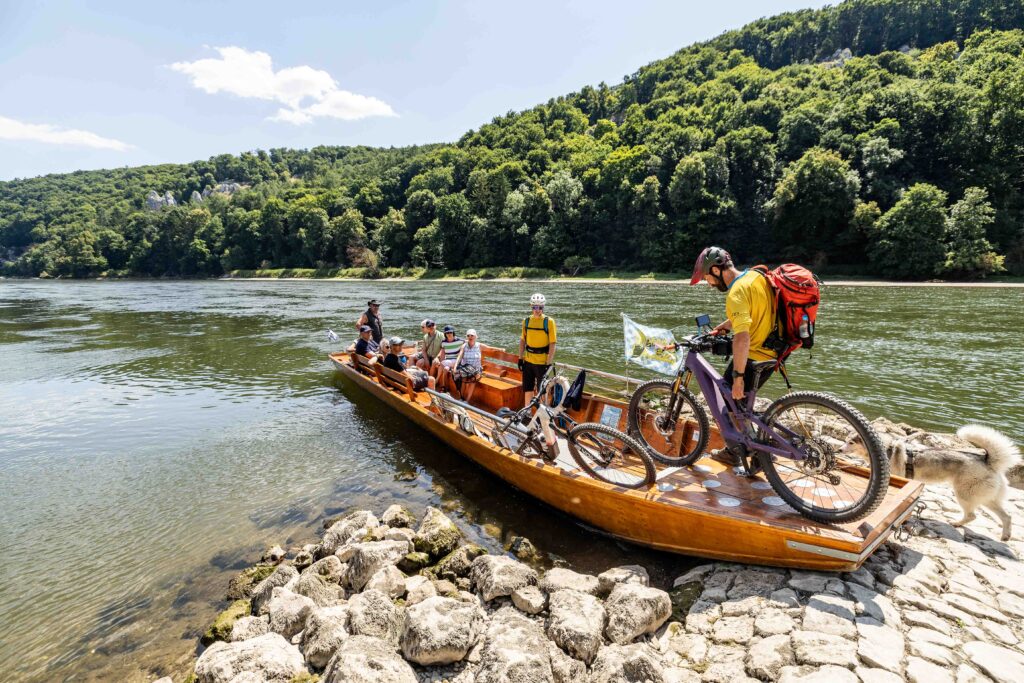 Mountainbiker steigen mit ihren Bikes aus der Zille am Ufer der Donau bei Kelheim